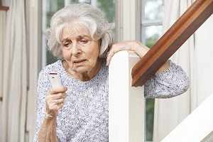 Unwell Senior Woman Using Personal Alarm At Home